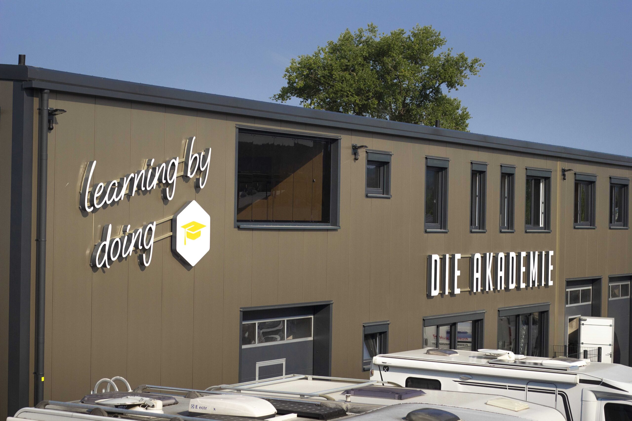 Das Akademiegebäude der Campingwelt Baden mit dem Leuchtschriftzug „Learning by doing“